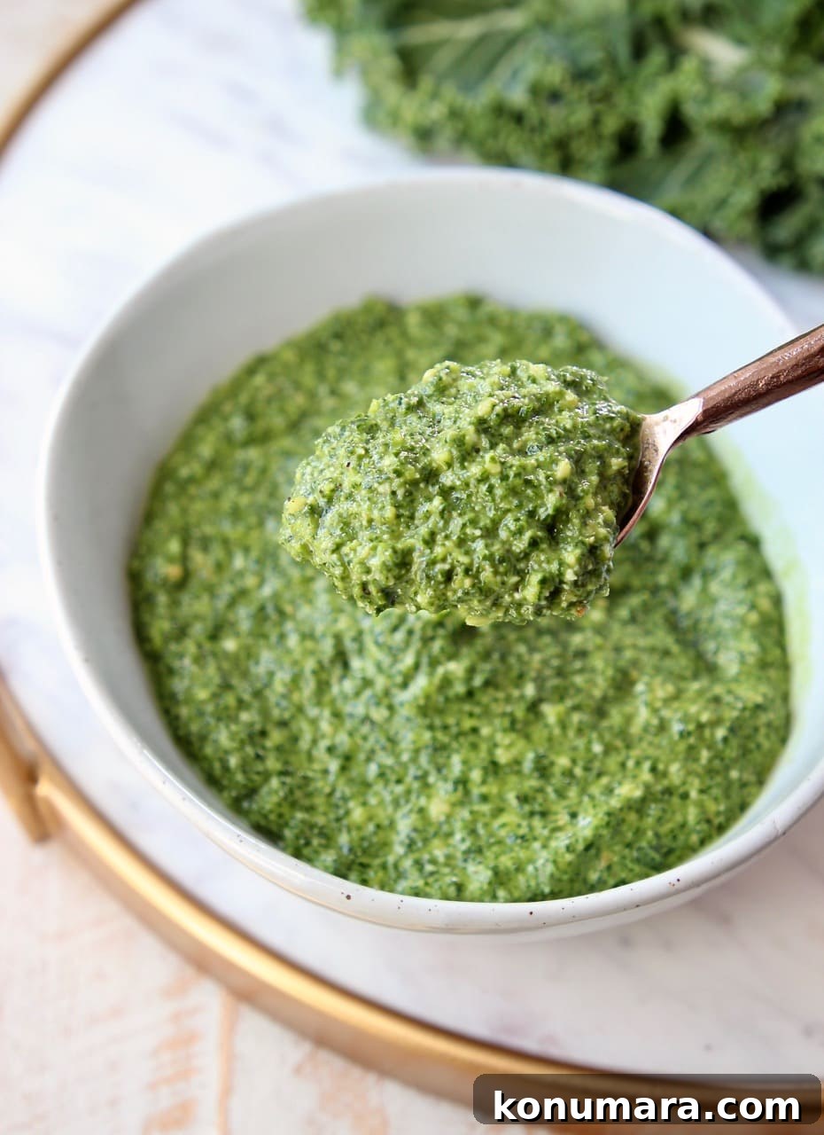 Kale pesto in copper spoon, coming out of bowl of pesto