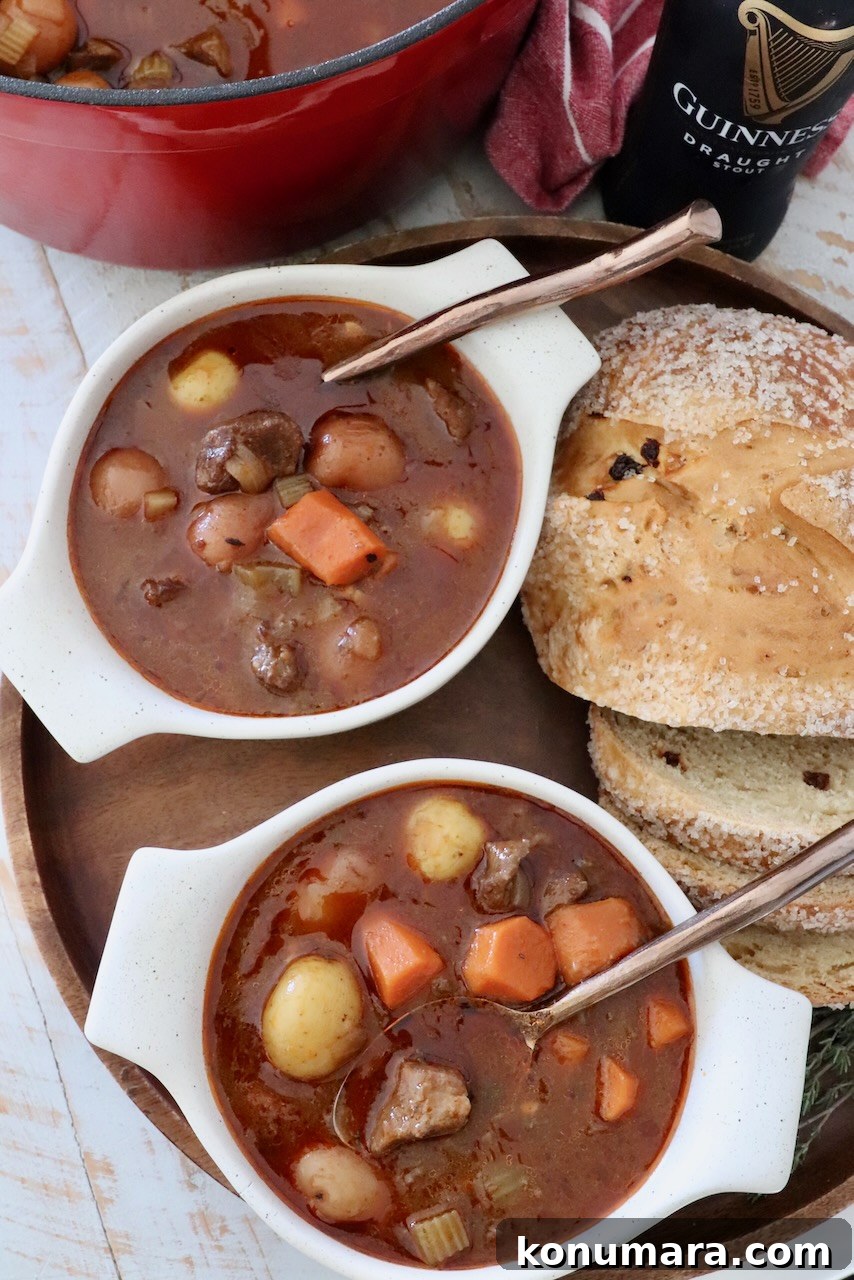 Irish stew in two bowls with spoons next to sliced bread