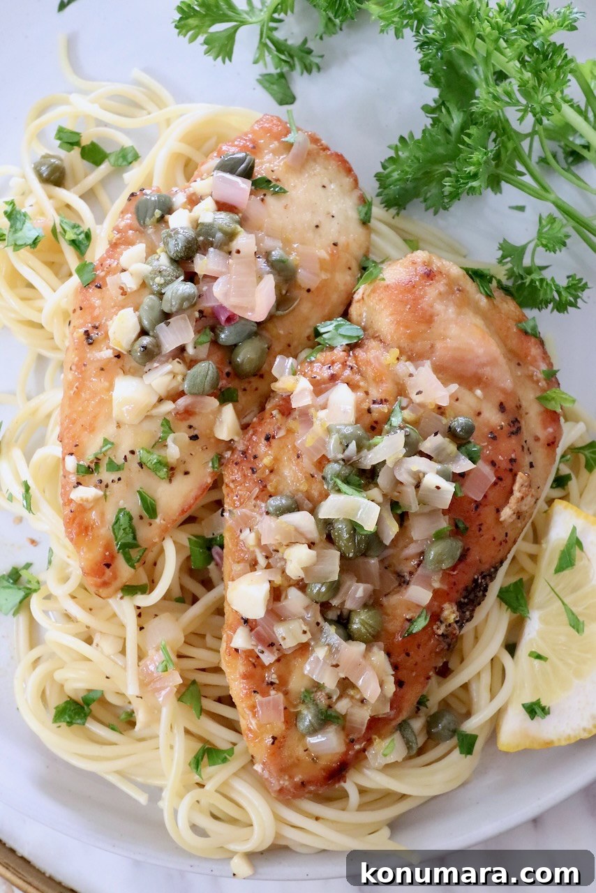chicken piccata on top of spaghetti noodles in a bowl
