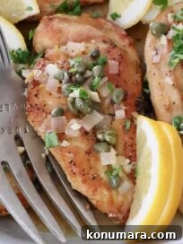 chicken piccata in a bowl with lemon wedges and a large serving fork
