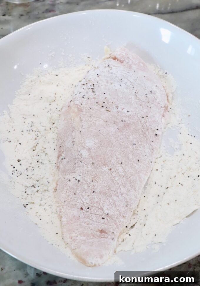 chicken breast covered in seasoned flour in a bowl