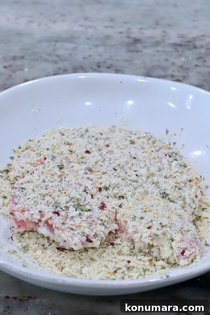 pork chop coated in seasoned breadcrumbs in a bowl