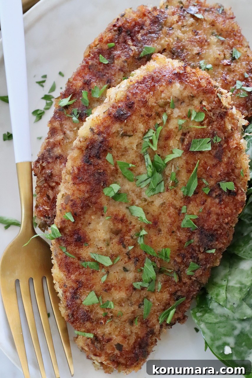 breaded cooked pork chops on a plate with a fork