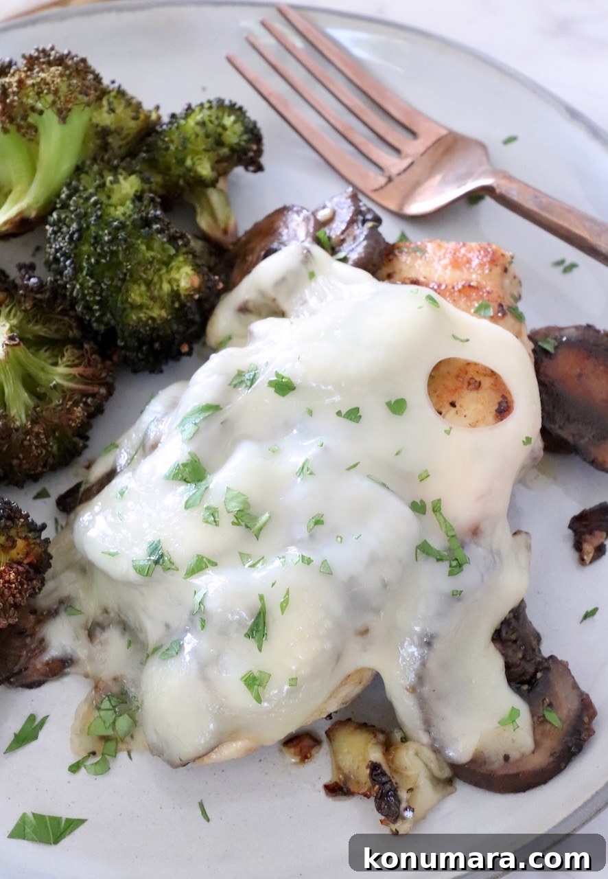 Pan Seared Chicken with Mushrooms and Swiss Cheese 12 chicken topped with mushrooms and melted cheese on a plate with broccoli