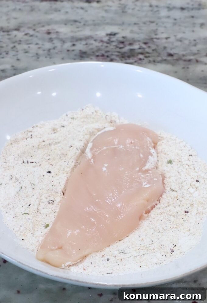 Pan Seared Chicken with Mushrooms and Swiss Cheese 5 a chicken breast in a bowl of seasoned flour
