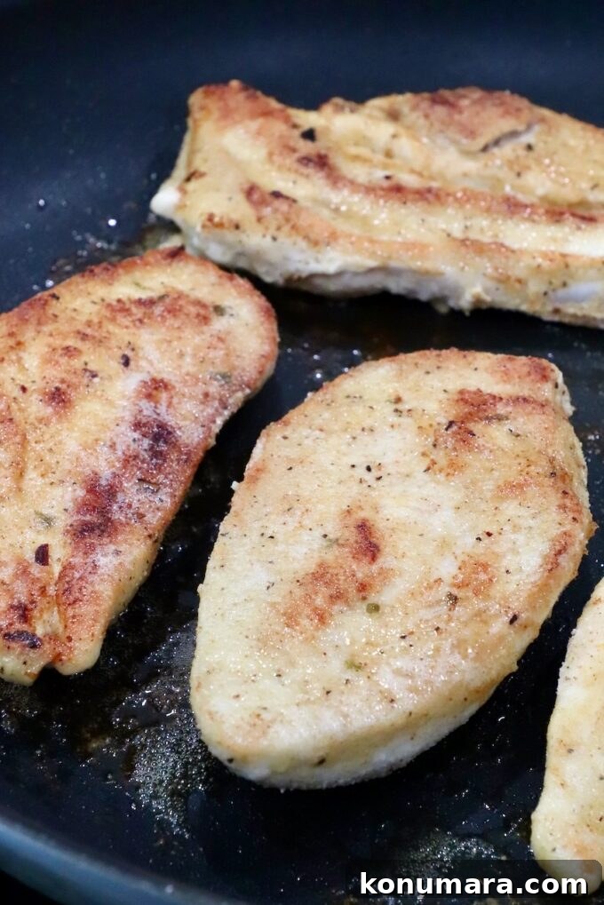 Pan Seared Chicken with Mushrooms and Swiss Cheese 7 browned chicken breasts in a skillet