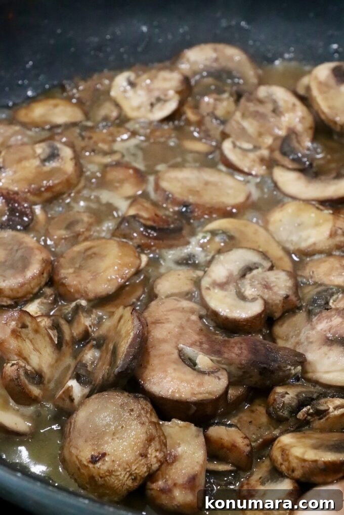 Pan Seared Chicken with Mushrooms and Swiss Cheese 8 sliced mushrooms cooking in a skillet