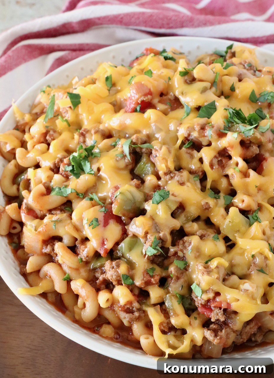 prepared goulash in a bowl topped with cheddar cheese