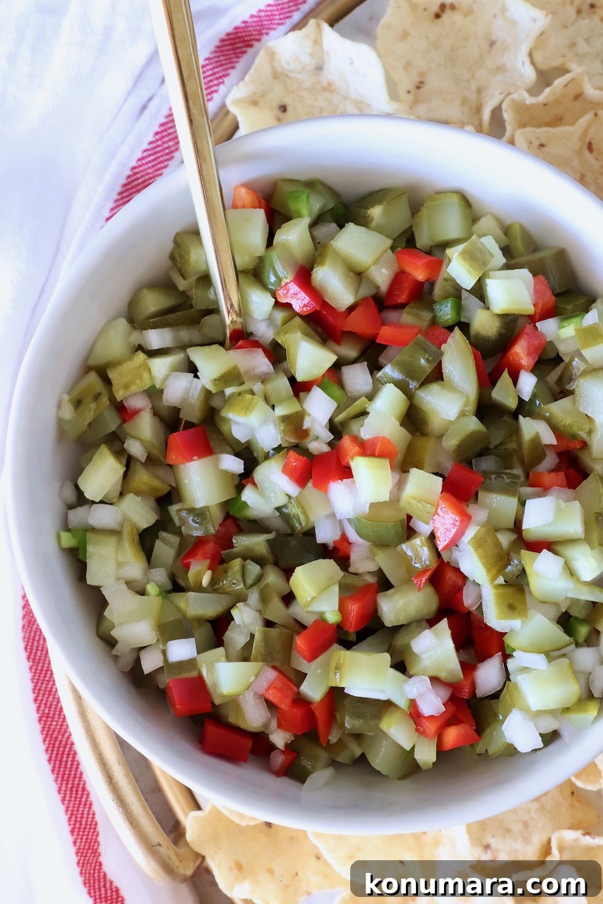 pickle de gallo in a bowl with a spoon surrounded by tortilla chips