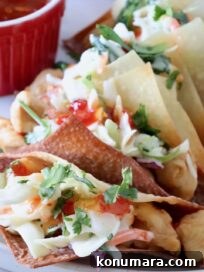 Wonton taco shells filled with cooked chicken and coleslaw on a plate