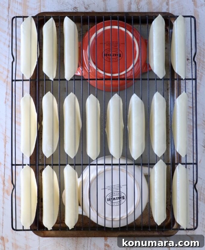 Wonton wrappers folded over a wire rack, on top of two bowls on a baking sheet