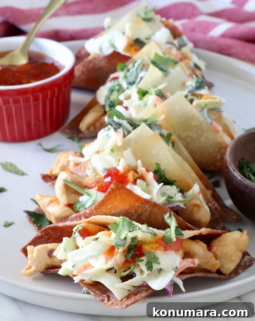 Chicken wonton tacos topped with sweet chili sauce on a plate