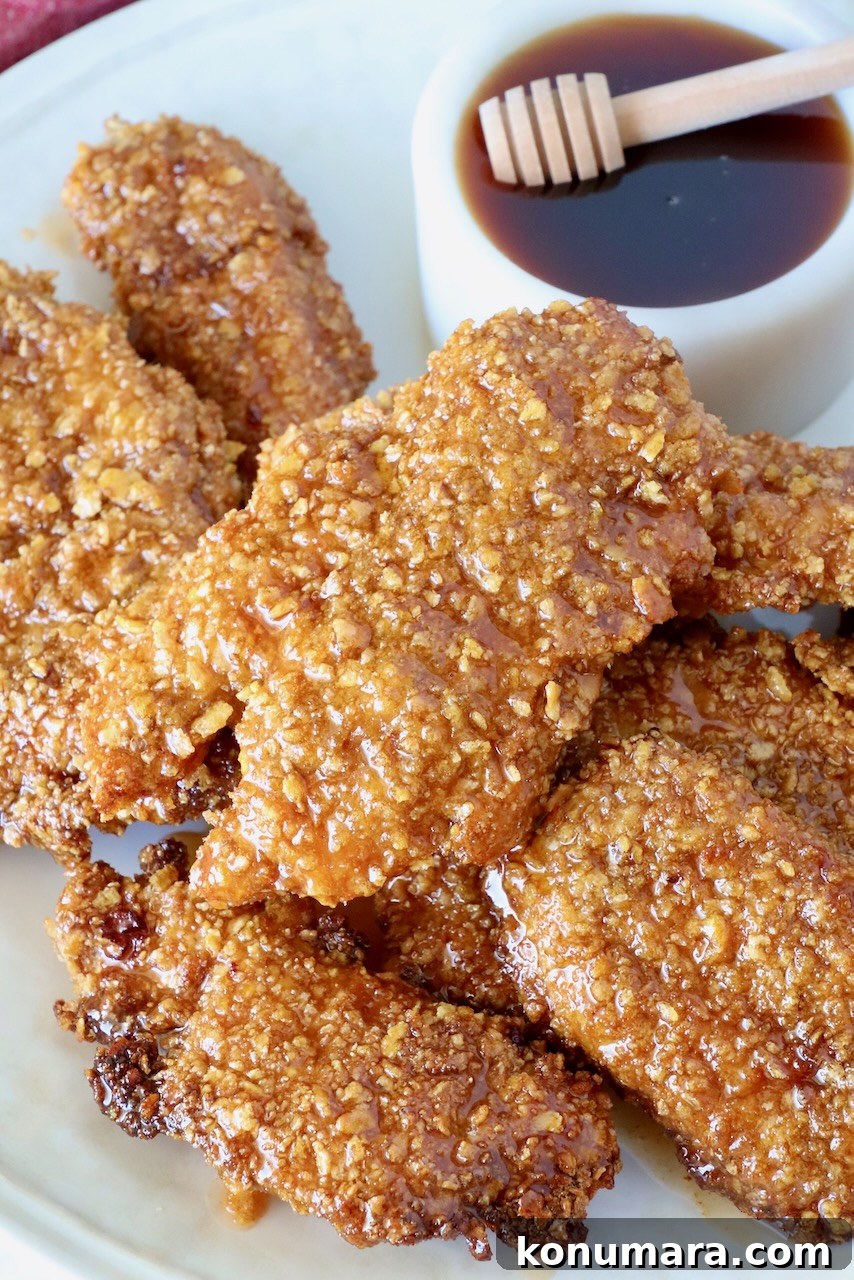 Hot Honey Glazed Chicken Recipe 6 Hot honey chicken tenders piled on a plate with a bowl of hot honey sauce