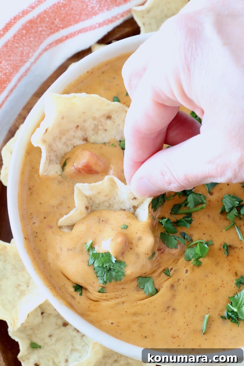 Creamy Chili Cheese Dip Recipe for Game Day 6 hand dipping a chip in a bowl of chili cheese dip