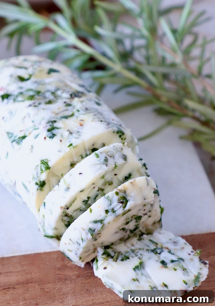 7 Homemade Compound Butter Recipes for Bread, Steak, and Veggies 2 compound butter sliced on a cutting board with fresh rosemary on the side