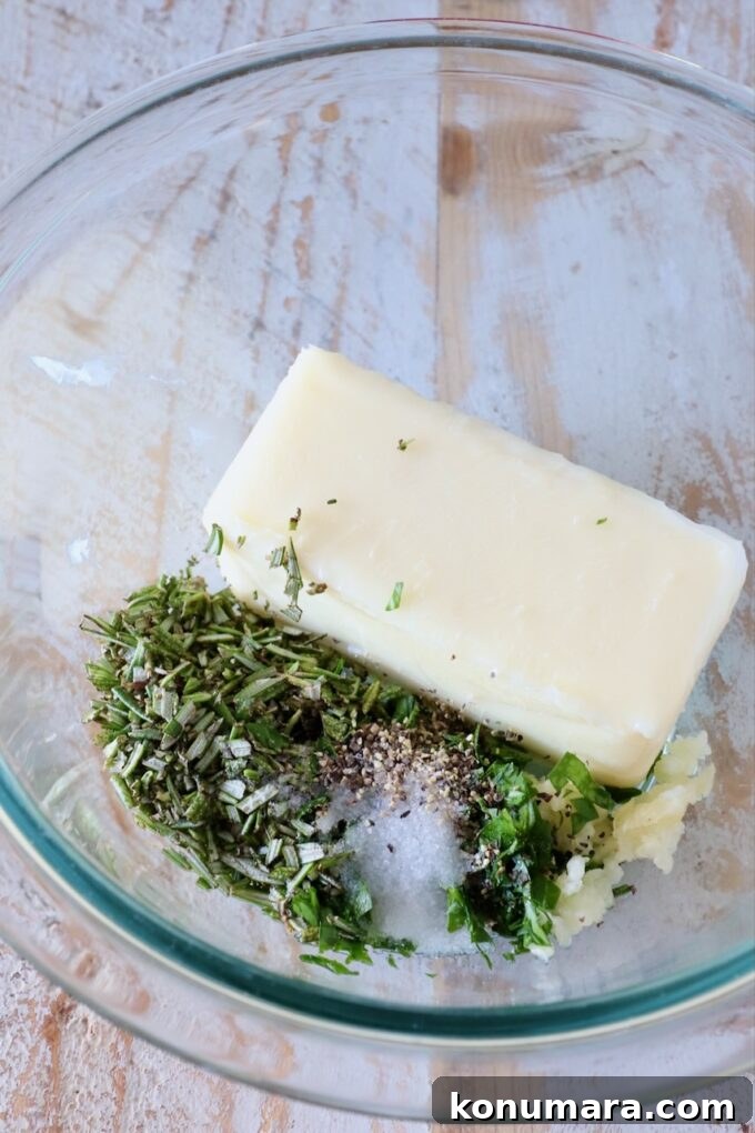 7 Homemade Compound Butter Recipes for Bread, Steak, and Veggies 4 a stick of butter in a glass bowl with herbs, garlic and salt
