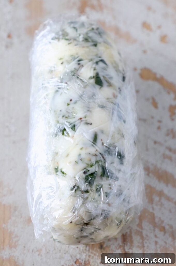 7 Homemade Compound Butter Recipes for Bread, Steak, and Veggies 6 compound butter wrapped up in plastic wrap on a white wood board