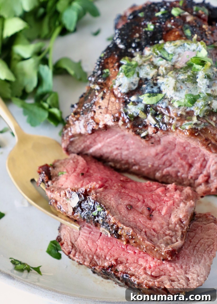 sliced filet mignon steak on a plate with a fork and fresh parsley