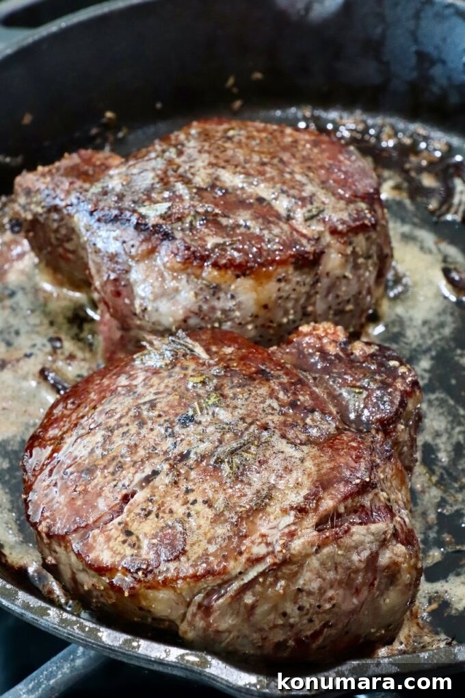 cooked steaks in a skillet with garlic rosemary butter