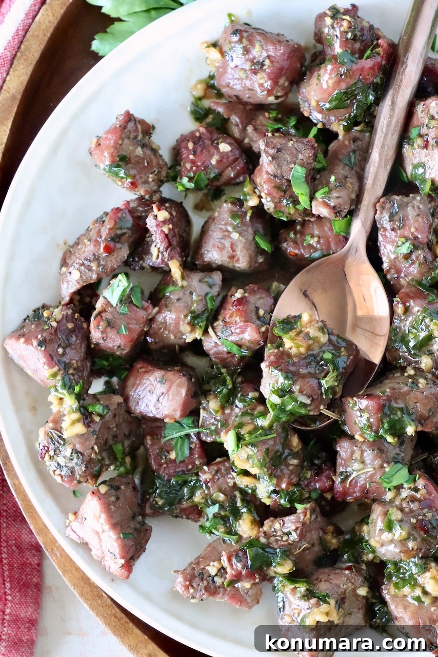 Garlic Butter Steak Bites Recipe: Juicy Pan-Seared Bites 2 steak bites covered in garlic herb butter on a plate with a spoon
