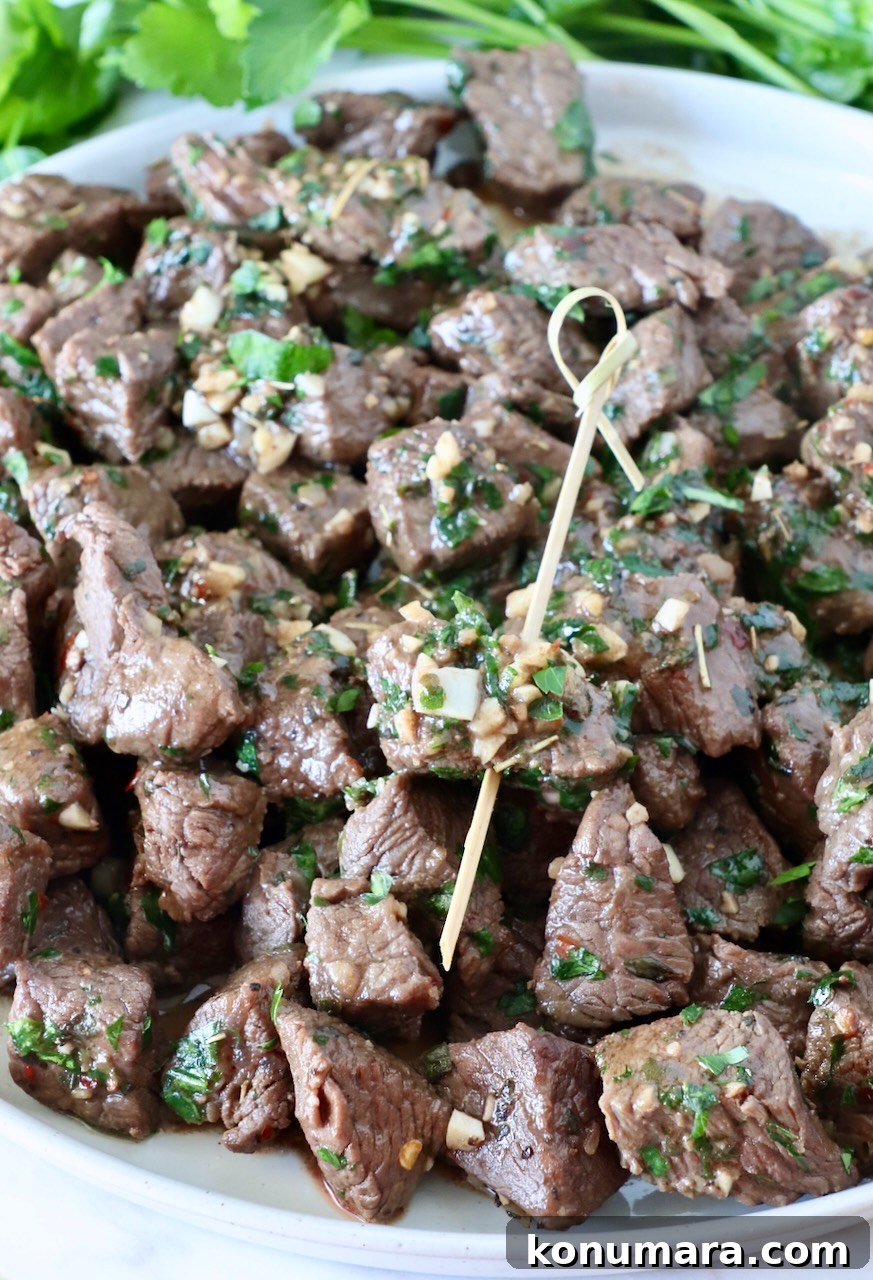 Garlic Butter Steak Bites Recipe: Juicy Pan-Seared Bites 9 steak bites on a plate with one bite skewered on a wooden pick