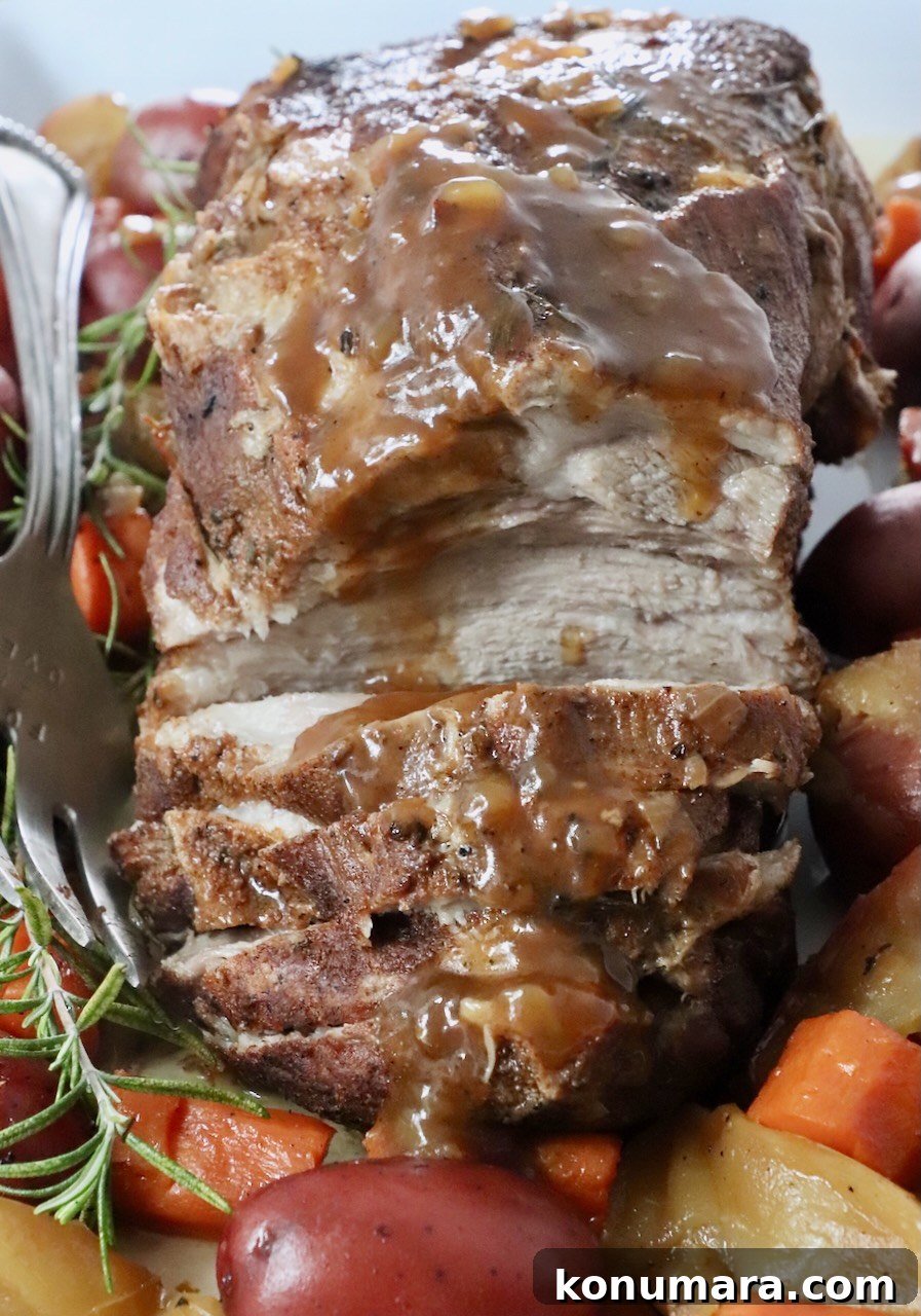 roasted pork on a serving platter with vegetables and rosemary