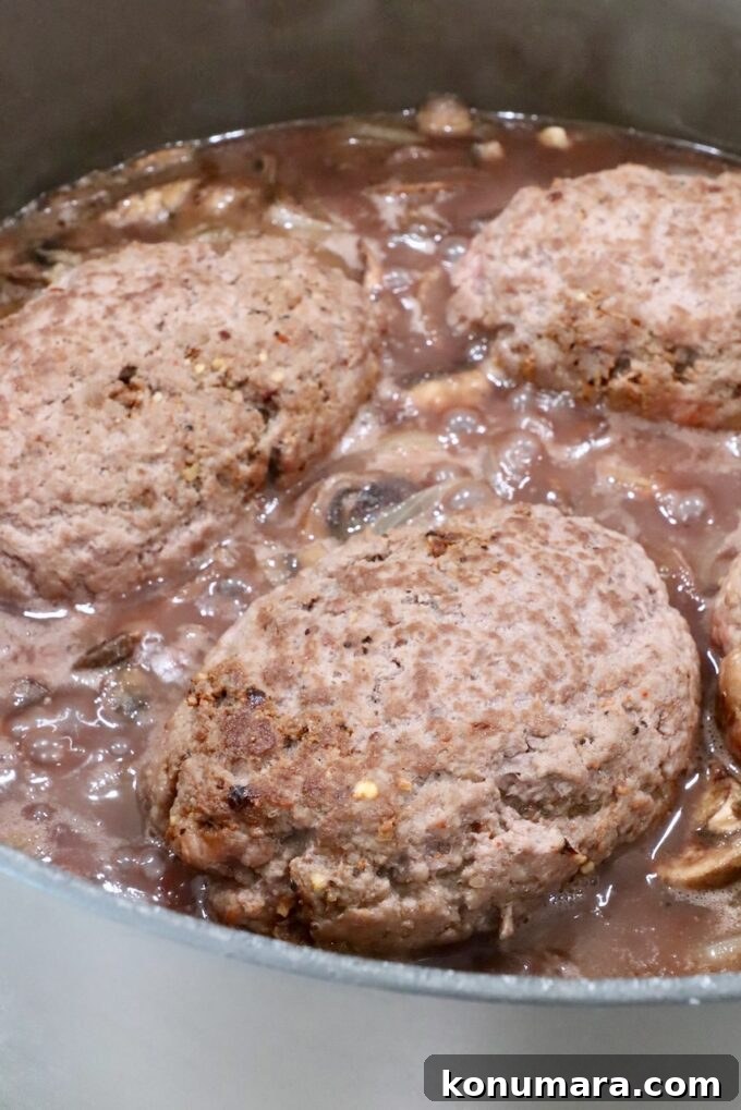 How to Make Chopped Steak with Mushroom Gravy 13 beef patties in pan with red wine gravy, mushrooms and onions