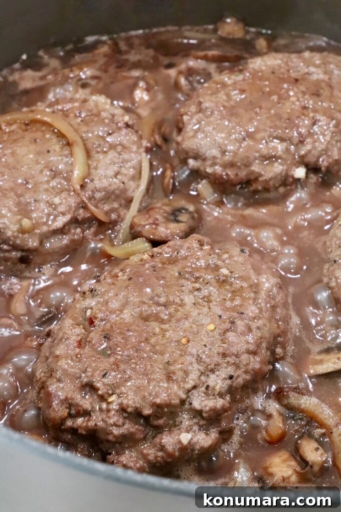 How to Make Chopped Steak with Mushroom Gravy 14 beef patties in pan with red wine gravy, mushrooms and onions