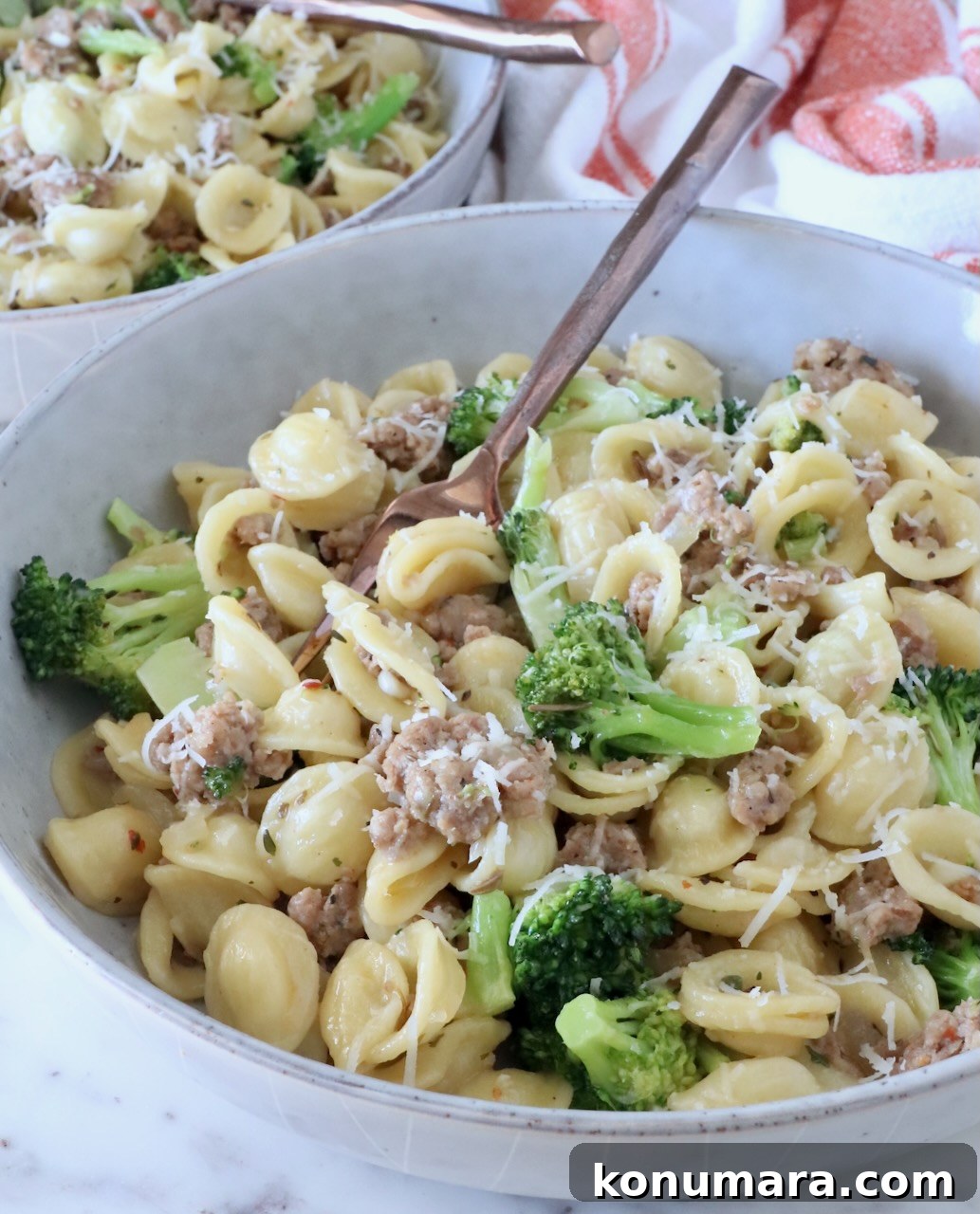 cooked orecchiette pasta with broccoli and cooked sausage in a bowl with a fork