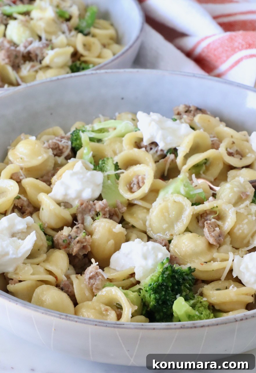 cooked orecchiette pasta with broccoli and sausage in a bowl topped with dollops of burrata cheese