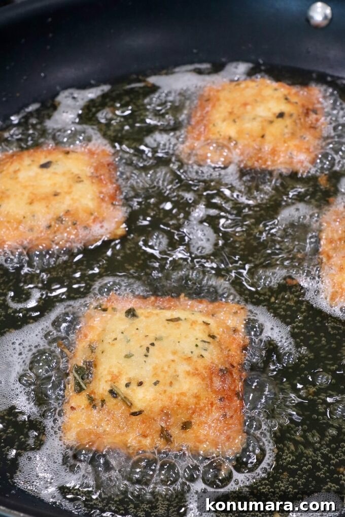 breadcrumb coated raviolis cooking in a skillet of oil