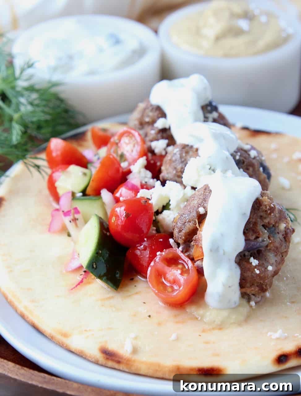 Greek meatballs on pita bread with tomato cucumber salad and tzatziki sauce on top