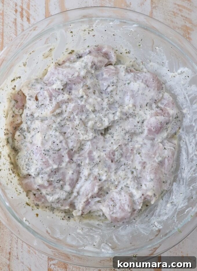 Homemade Greek Chicken Gyros Recipe 4 chicken thighs in a seasoned yogurt marinade in a large glass bowl