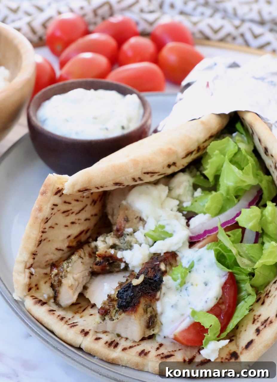 Homemade Greek Chicken Gyros Recipe 9 pita bread filled with chicken gyros meat, tzatziki sauce, shredded lettuce, sliced onions and tomatoes, on a plate