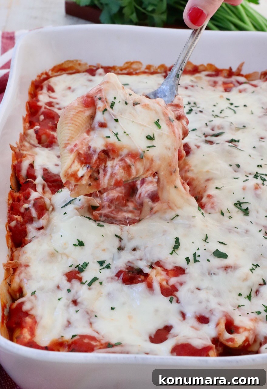 Ricotta Stuffed Shells Recipe with Spinach 10 cheese filled stuffed pasta shell lifted out of a casserole dish with a serving spoon