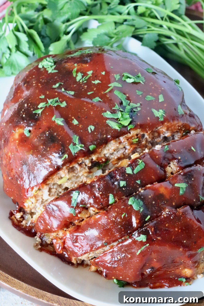 30-Minute Air Fryer Meatloaf Recipe with Crispy Edges 11 glazed cooked meatloaf sliced on a plate with fresh parsley