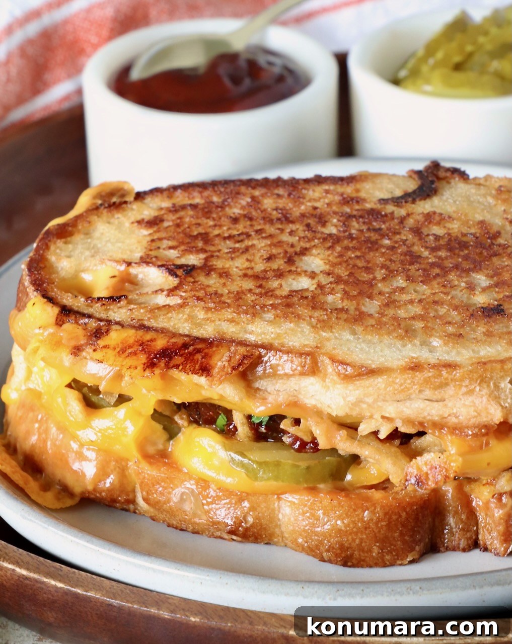 How to Make a Classic Meatloaf Sandwich 2 meatloaf sandwich on a plate with a small bowl of bbq sauce and small bowl of pickles behind the sandwich