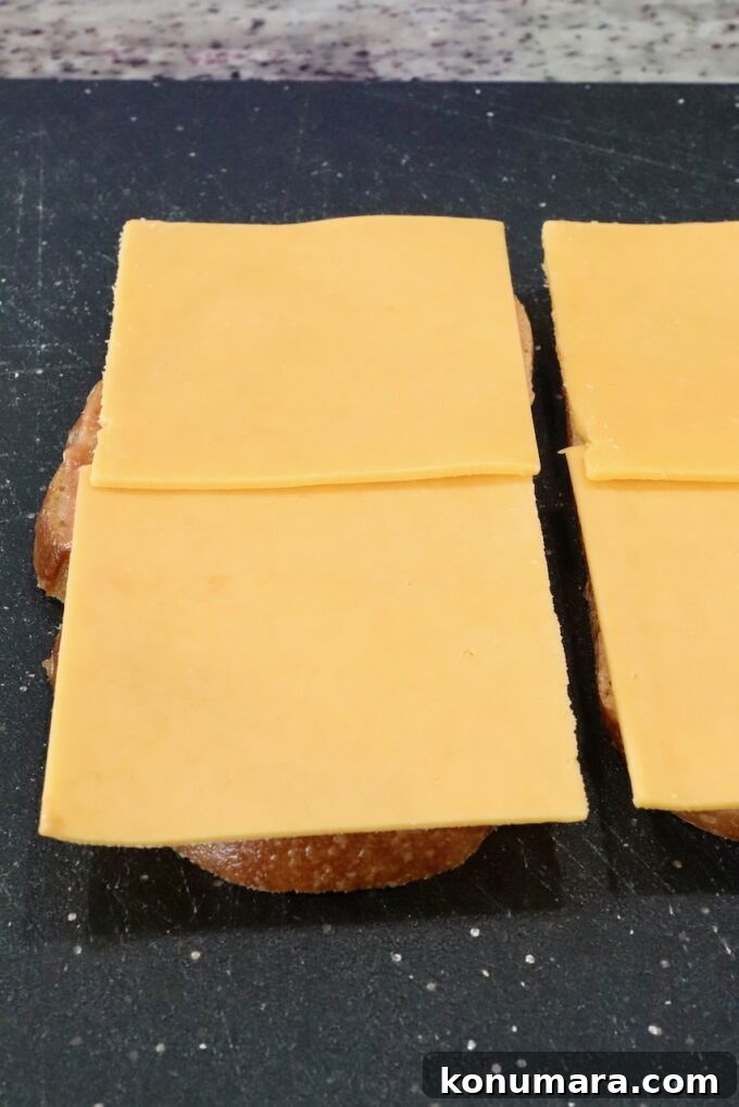 How to Make a Classic Meatloaf Sandwich 5 slices of cheddar cheese placed on two slices of bread on a cutting board