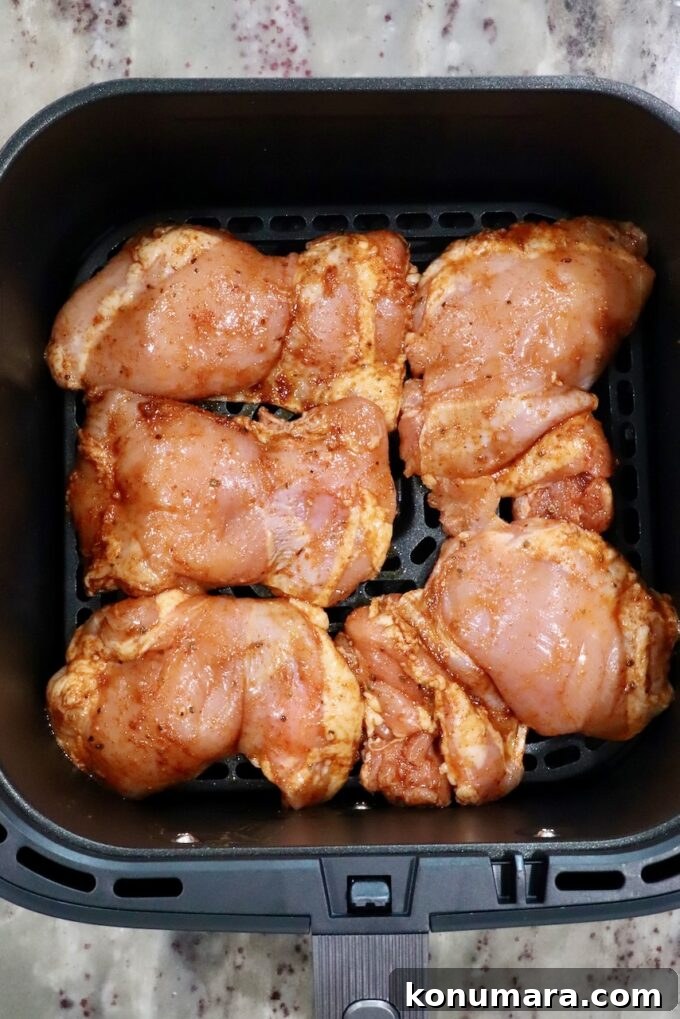 seasoned, raw chicken thighs in an air fryer basket