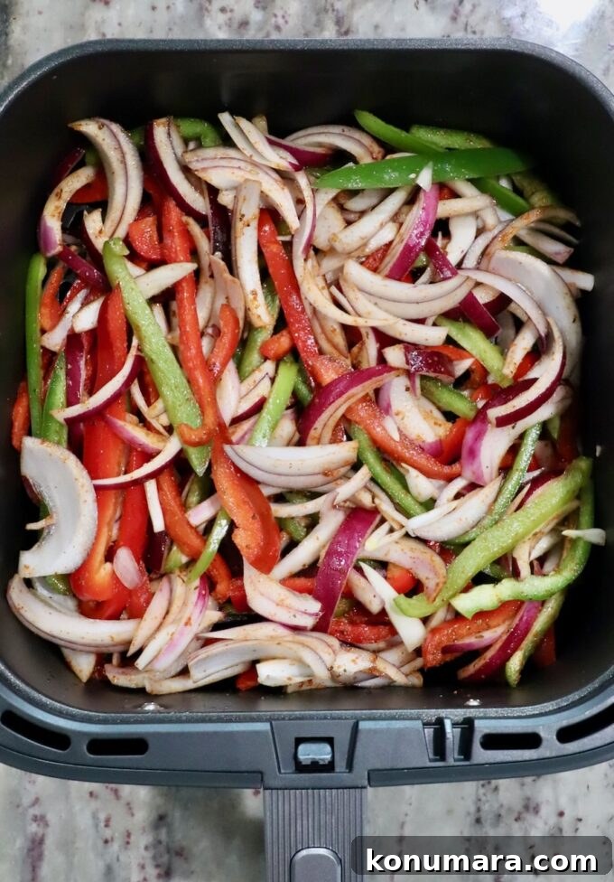 sliced bell peppers and red onions in an air fryer basket