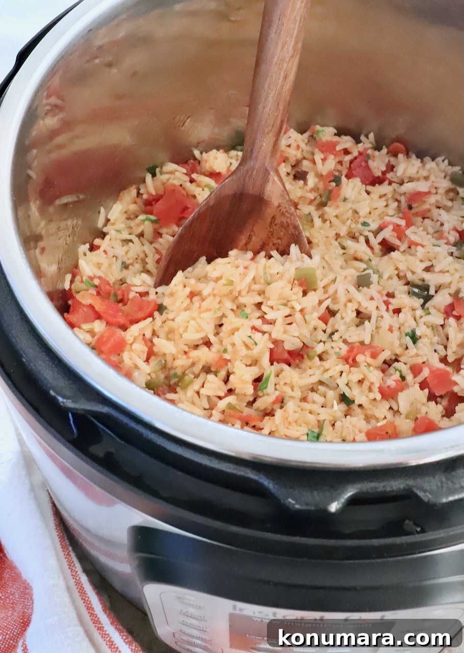 cooked Mexican rice in an Instant Pot with a large wooden spoon