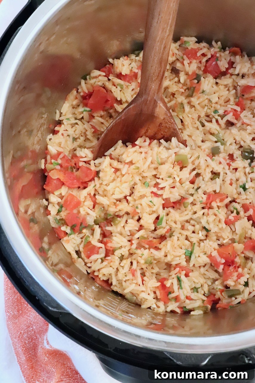 Mexican rice in an Instant Pot with a large wooden spoon