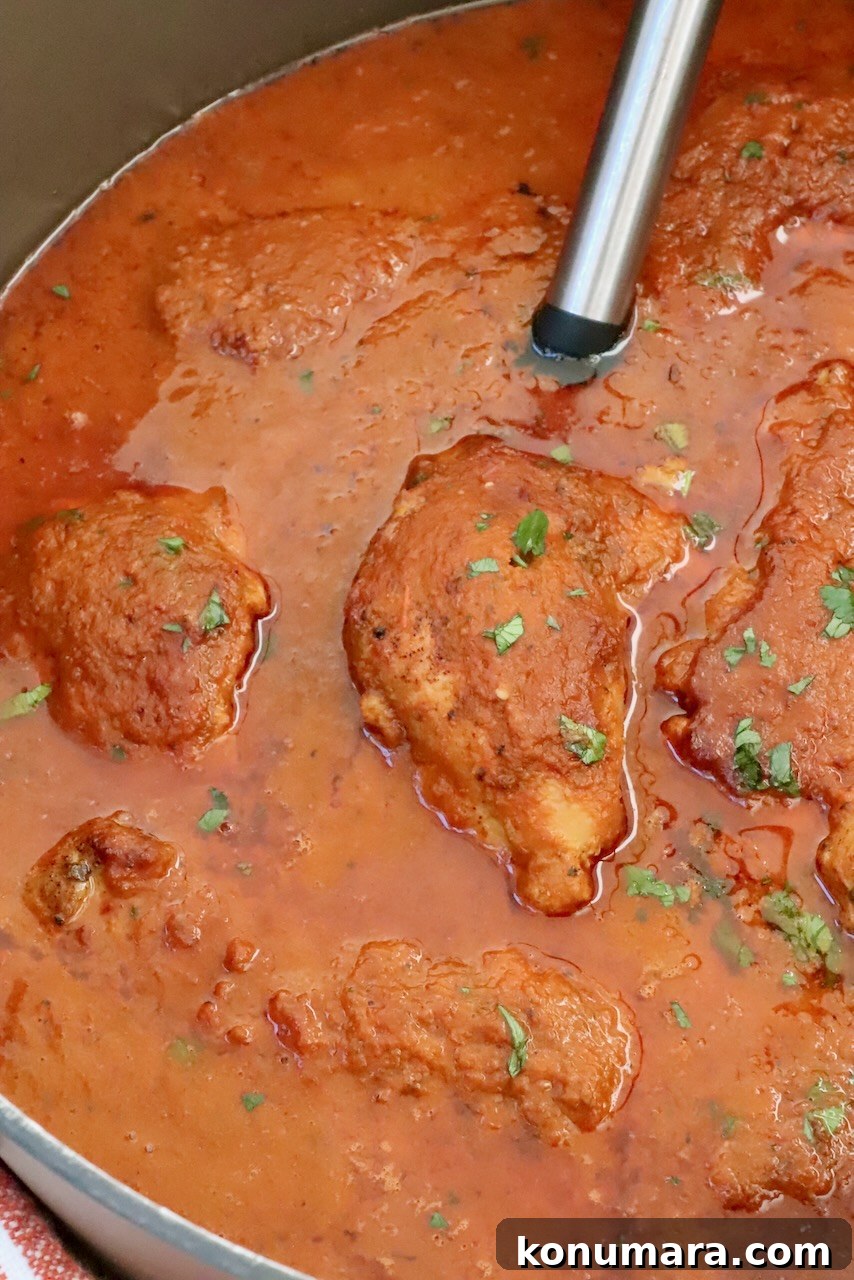 Classic Mexican Chicken Adobo Recipe 8 chicken covered in adobo sauce in a large pot with a serving spoon