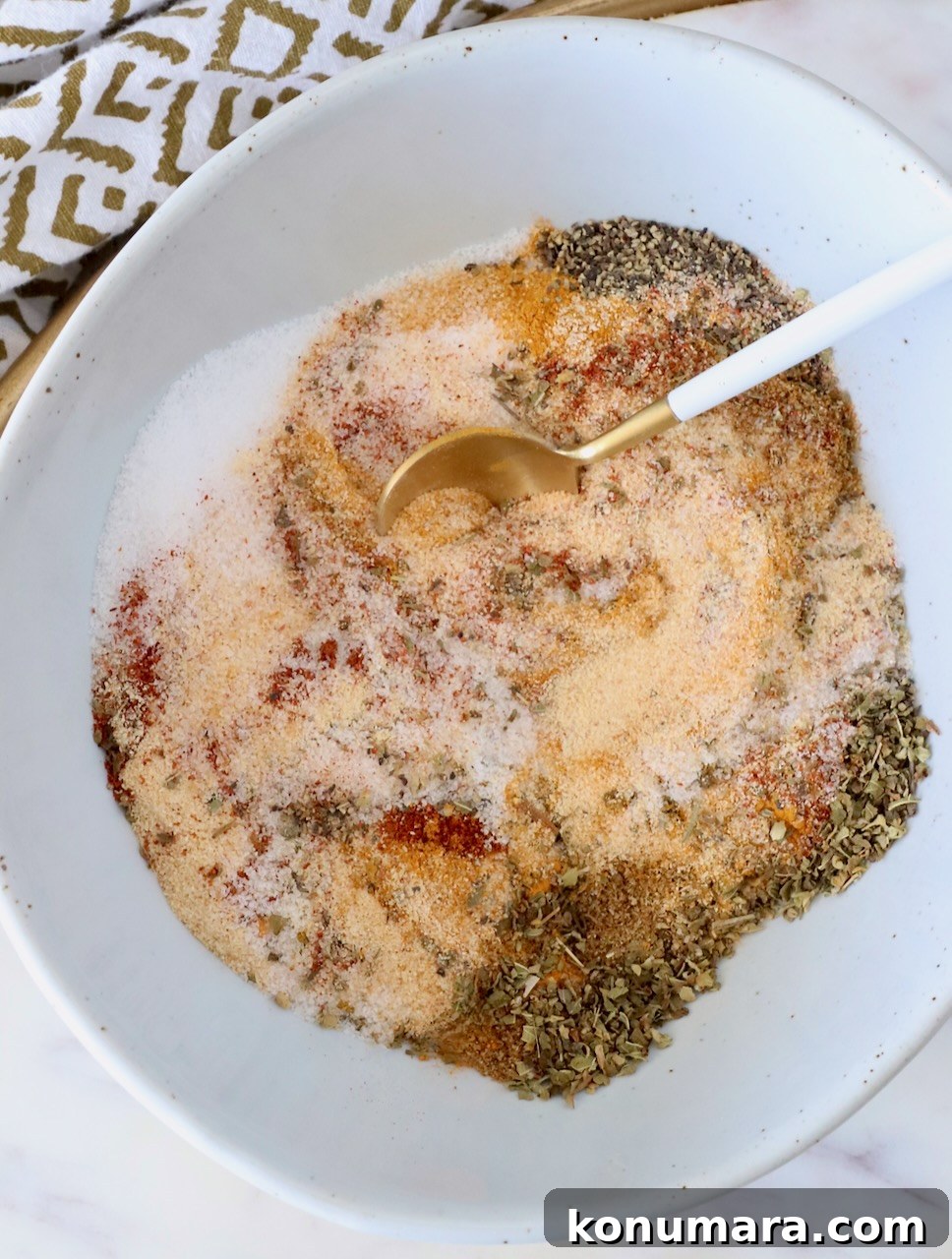 Homemade Adobo Seasoning Mix for Authentic Flavor 2 various dried herbs and spices mixed together in a bowl with a small spoon