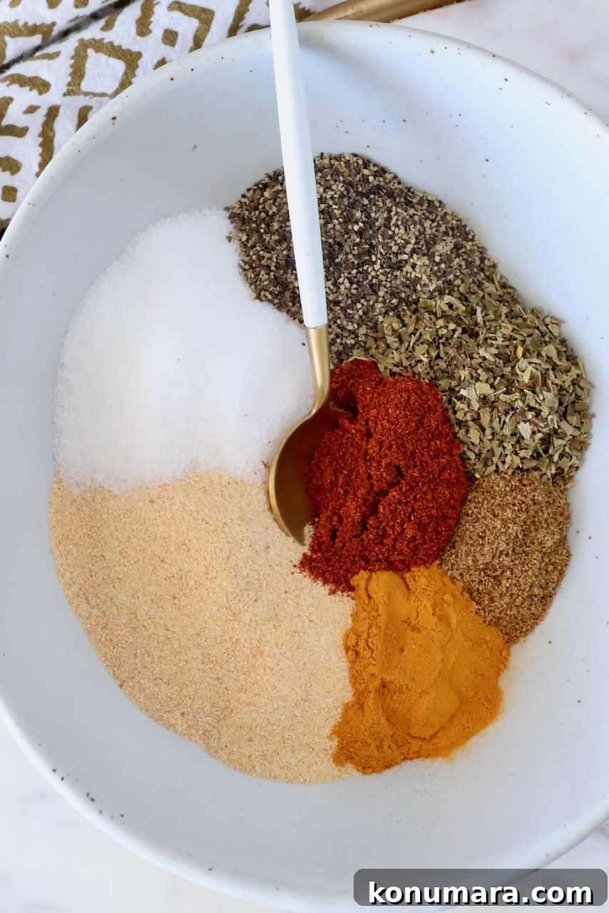 Homemade Adobo Seasoning Mix for Authentic Flavor 5 dried herbs and spices separated in a bowl with a spoon