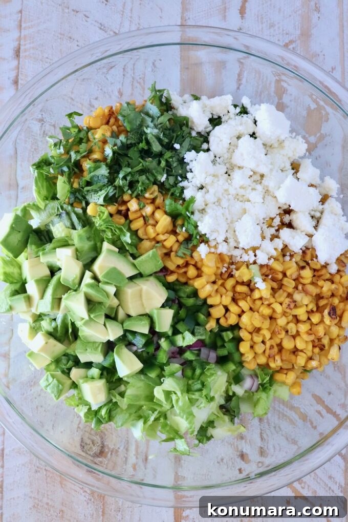 corn, avocado, cotija cheese, cilantro and chopped lettuce in a large glass bowl
