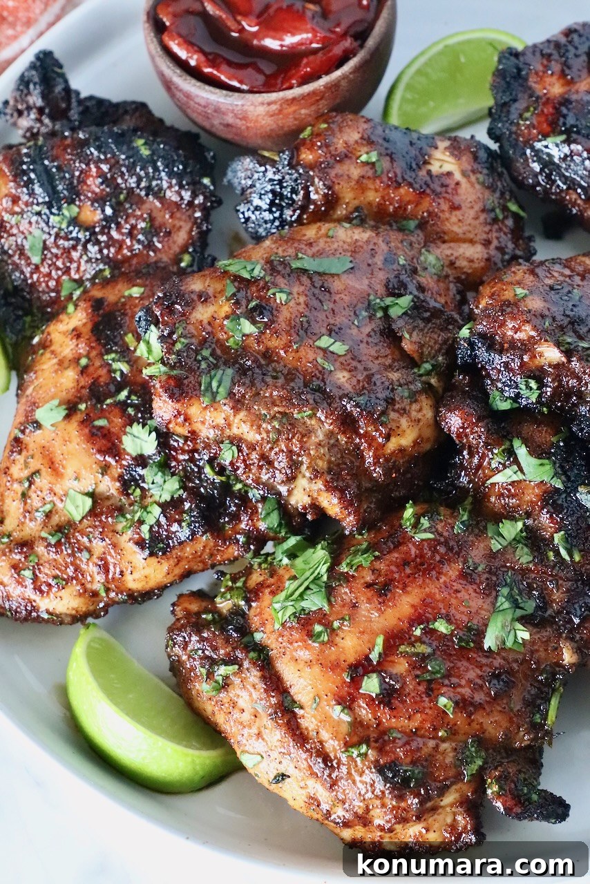 Chipotle Honey Glazed Chicken Recipe 13 Grilled chicken thighs stacked on a plate with lime wedges and chipotle peppers in a small bowl