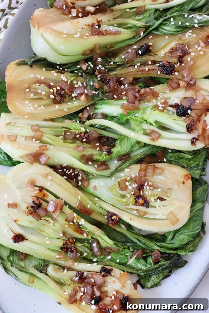 How to Cook Baby Bok Choy: Quick Stir-Fry Recipe and Tips 2 cooked baby bok choy topped with garlic shallot soy sauce on a plate