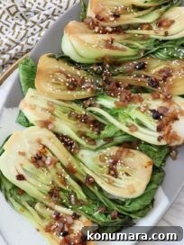 cooked baby bok choy on a plate covered in garlic shallot soy sauce