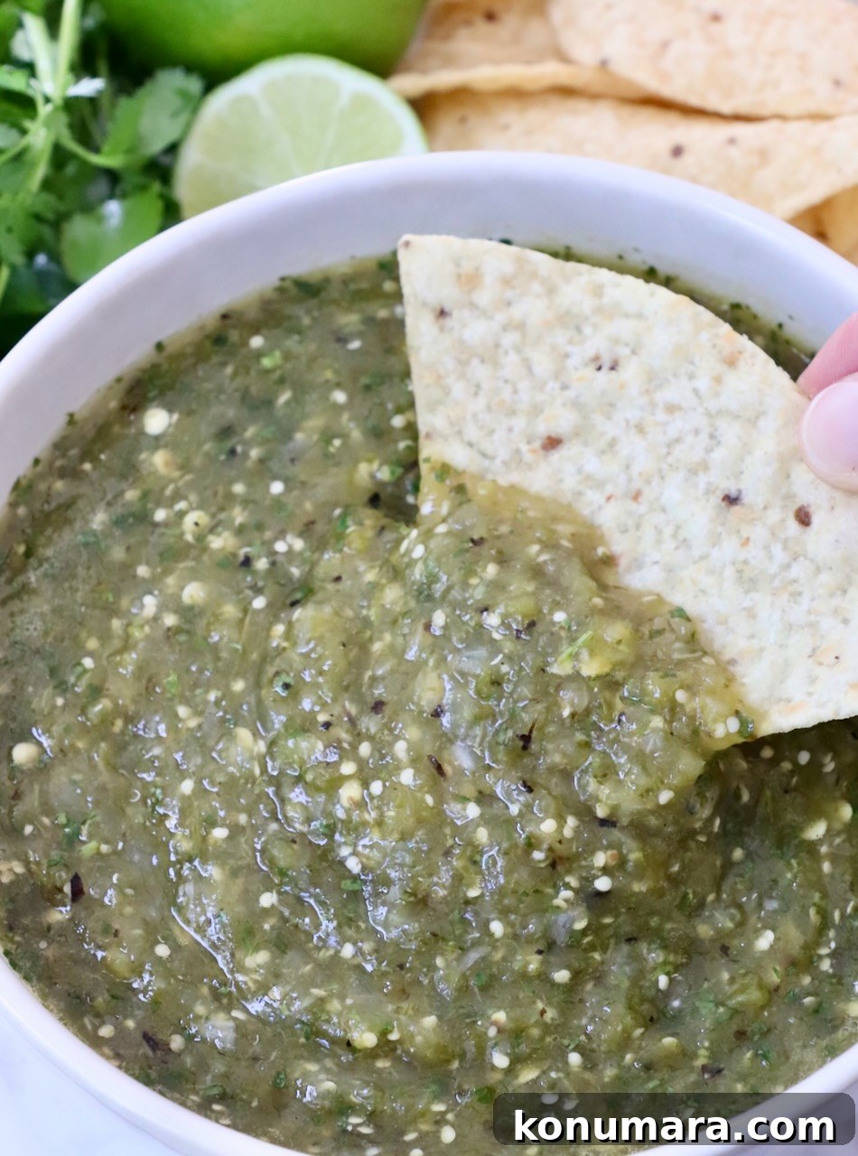 tortilla chip dipped is salsa verde in a bowl